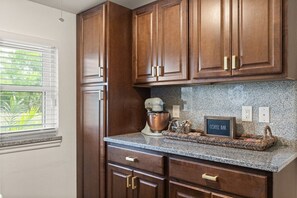 A kitchen with wooden cabinets, a granite countertop, and a coffee bar sign.