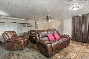 A living room with leather recliners, a ceiling fan, and a patterned rug.