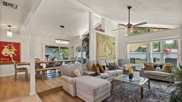 A spacious living area with a large sectional sofa, a glass coffee table, and a ceiling fan.