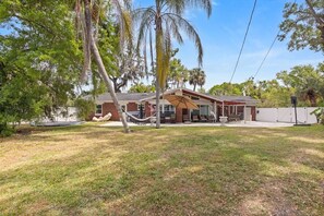 A residential property with a covered patio, a hammock, and a fenced yard.