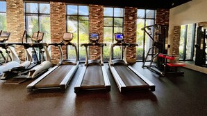 Un gimnasio con cintas de correr, bicicletas estáticas y máquinas de pesas.