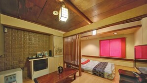 A compact hotel room with a wooden ceiling, a bed with a red headboard, a small desk with a computer, a wooden table with a drink menu, and a red-framed window. - HOTEL IS (Yokohama)