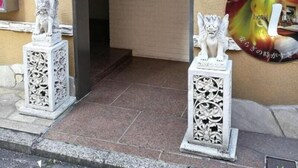 An entrance with a stone archway, two white statues on pedestals, and a wall-mounted light fixture. - HOTEL IS (Yokohama)