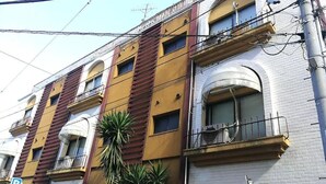 A multi-story building with a yellow facade, balconies, and a parking sign. - HOTEL IS (Yokohama)