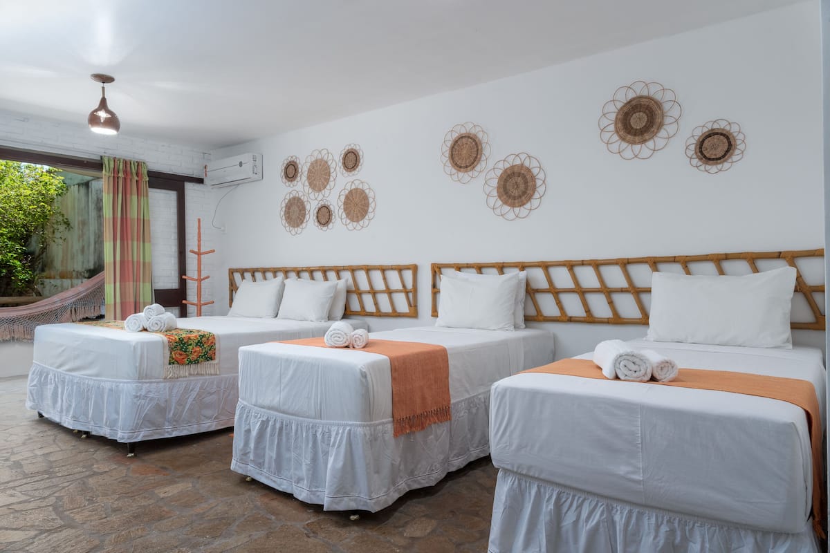 Ein Hotelzimmer mit drei Betten, einer Hängematte und Wanddekoration.
