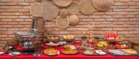 A buffet table with various food items and baskets against a brick wall.