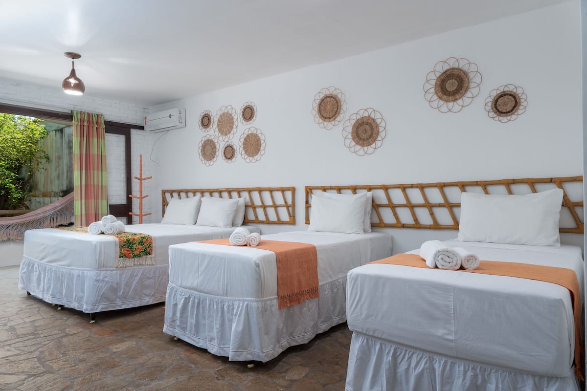 Ein Hotelzimmer mit drei Betten, einer Hängematte und dekorativer Wandkunst.