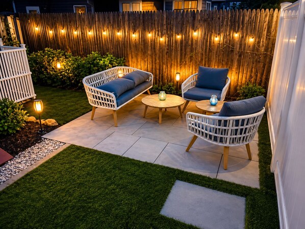 A patio with wicker furniture, a round table, and string lights.