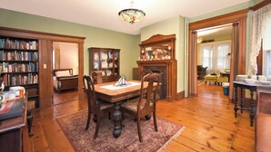 A dining room with a wooden table, chairs, a chandelier, and a fireplace. - Blooming Inn (Shelburne Falls)