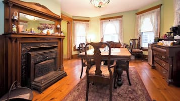 A dining room with a wooden table, chairs, a chandelier, and a fireplace.
