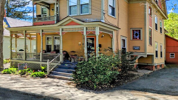 A two-story house with a porch, a balcony, and a chimney. - Blooming Inn (Shelburne Falls)