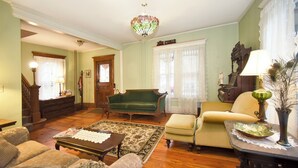 A traditional living room with a green sofa, a yellow armchair, a wooden coffee table, and a patterned rug. - Blooming Inn (Shelburne Falls)
