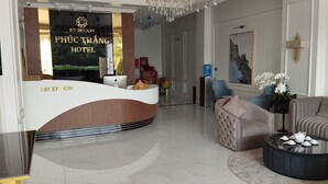 A hotel reception area with a modern design, featuring a reception desk, seating area, and a chandelier. - PHUC THANG HOTEL (Phu Quoc)