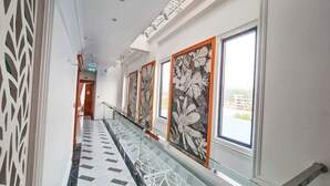 A hallway with patterned floor tiles, glass railings, and large windows with floral artwork. - PHUC THANG HOTEL (Phu Quoc)