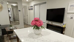 Une cuisine moderne avec un plan de travail en marbre blanc, des bancs en bois et un vase rempli de fleurs roses.