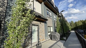 Un bâtiment moderne à deux étages, doté d’une façade en pierre, de grandes fenêtres et d’un espace extérieur aménagé avec des sièges.