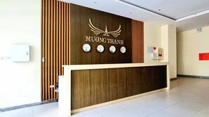 A reception desk with a wooden panel design, a ceiling fan, and four wall clocks. - Muong Thanh Apartment Luxury 03 bedroom (Da Nang)