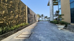 A paved walkway with a decorative wall on one side and a modern building on the other. - Muong Thanh Apartment Luxury 03 bedroom (Da Nang)