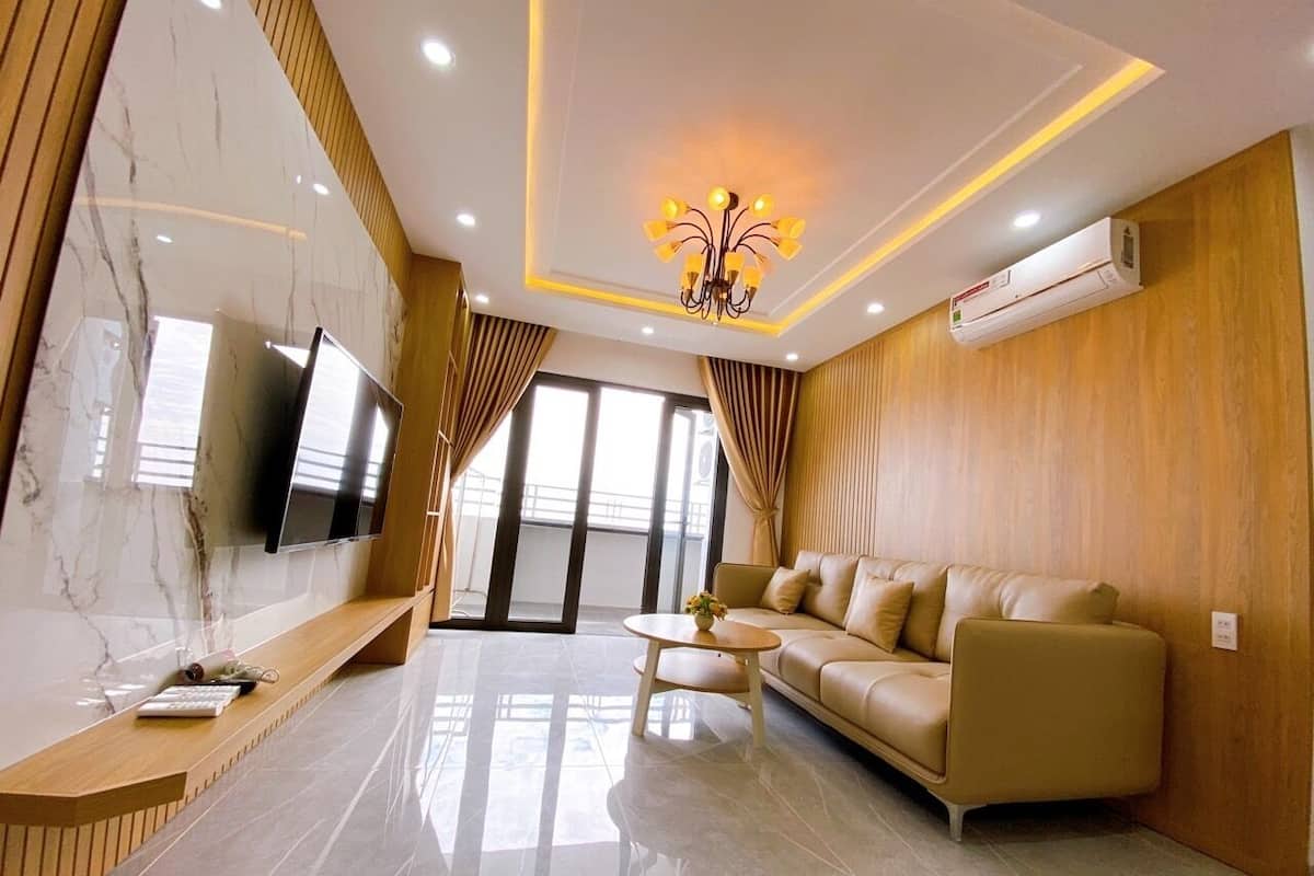 A modern living room with a sofa, a coffee table, and a TV mounted on a marble wall.