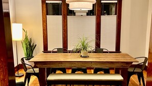 A wooden dining table with a bench, surrounded by chairs, in a room with wooden flooring and a ceiling light fixture. - 1912 Historic Ballard Craftsman
5 Bed • 2 Bath • Yard • Parking (Seattle)