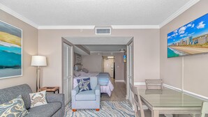 A modern hotel room with a sofa, a dining table, a bed with a view, and a painting on the wall. - Amazing OCEAN FRONT Views!  Newly Renovated!   Walking Distance to All  Myrtle.  (Myrtle Beach)