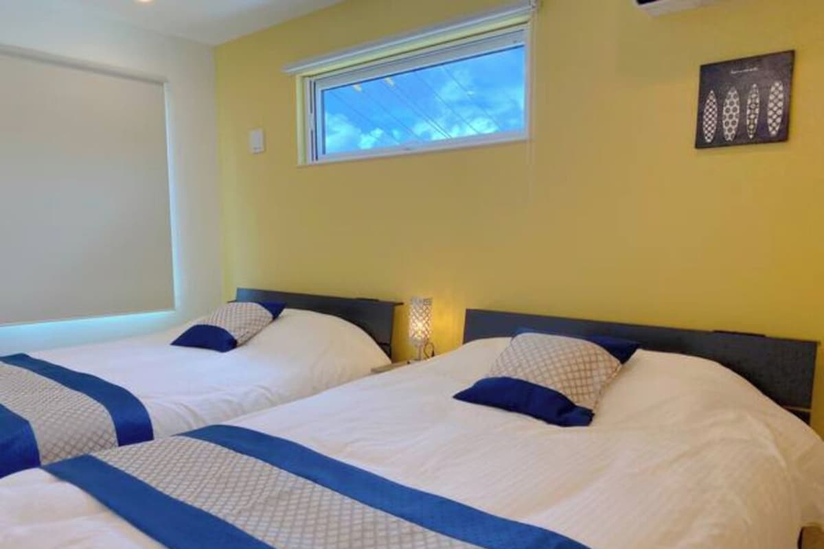 A hotel room with two beds, a window with a view, and a wall-mounted artwork.