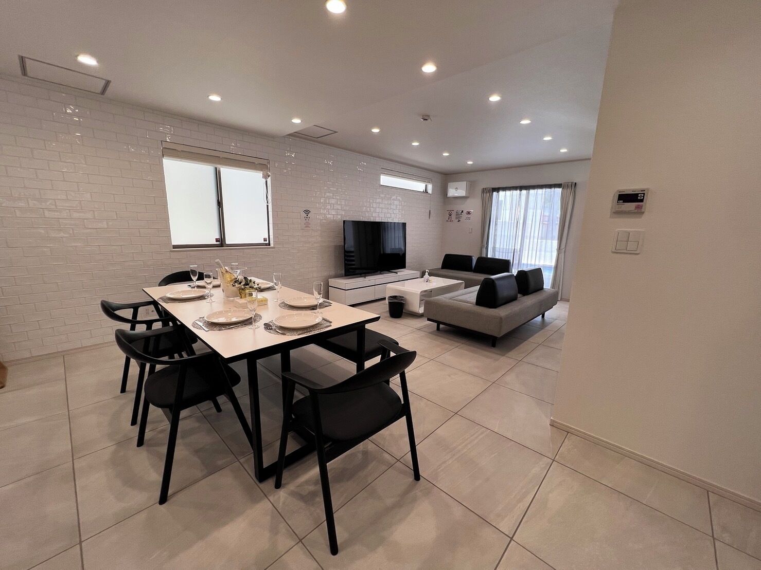 A modern living room with a dining area, a sofa set, and a flat-screen TV.
