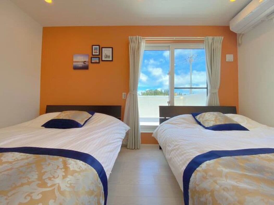 Una habitación de hotel con dos camas, una ventana con cortinas y vistas al cielo.