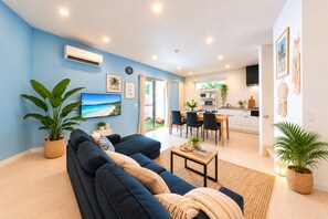 A modern living room with a blue wall, a sofa, a dining area, and a kitchen. - Grandioso Okinawa Pool Villa Onna 7 (Onna)