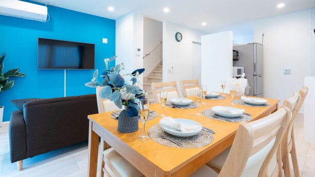 A modern dining area with a wooden table set for four, surrounded by white chairs. - Grandioso Okinawa Pool Villa Onna 7 (Onna)