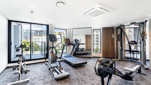 Un gimnasio moderno con máquinas de cardio, equipo de entrenamiento con pesas y grandes ventanales con vistas a la ciudad.
