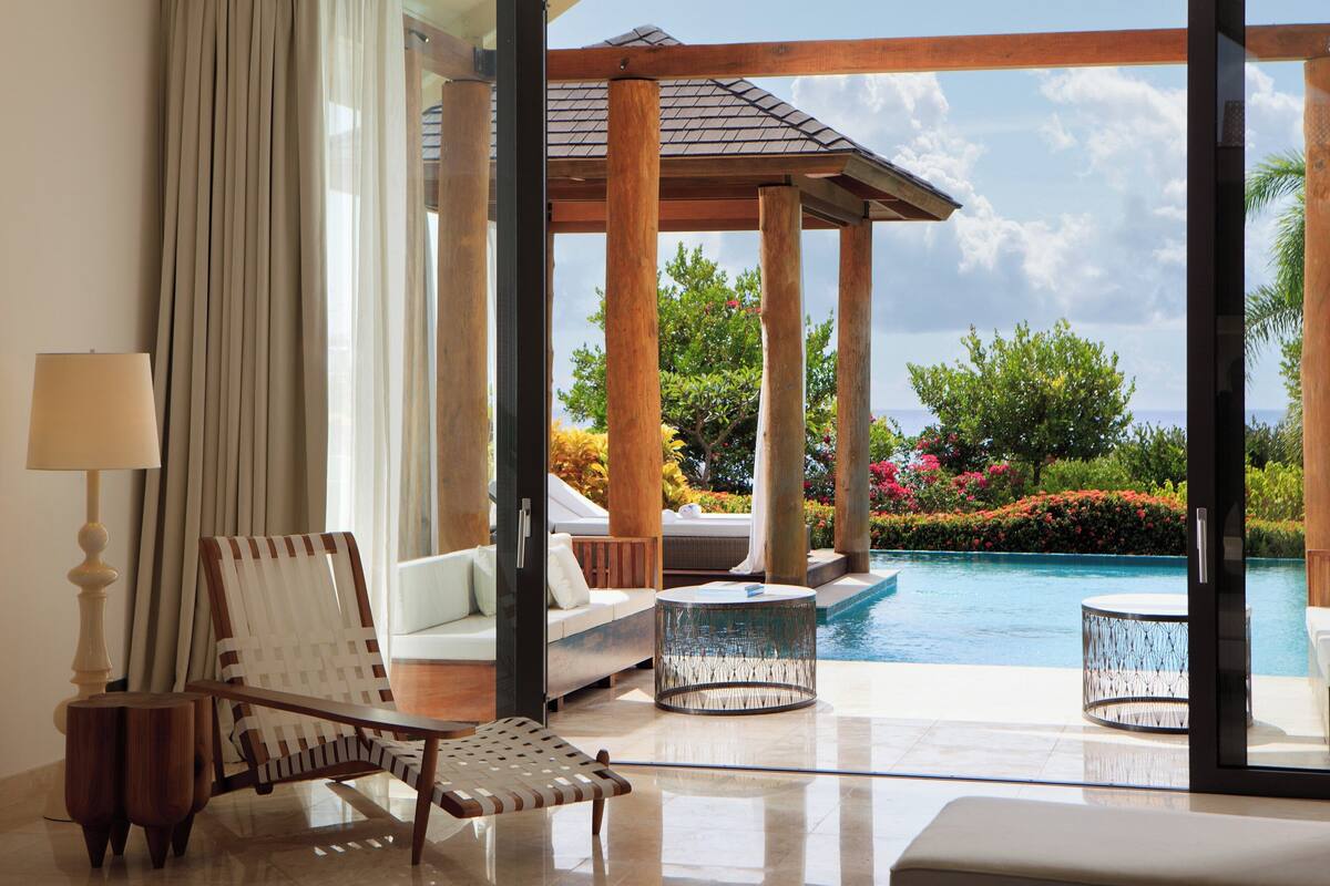 A modern room with a view of a swimming pool, a sofa, a chair, and a lamp.