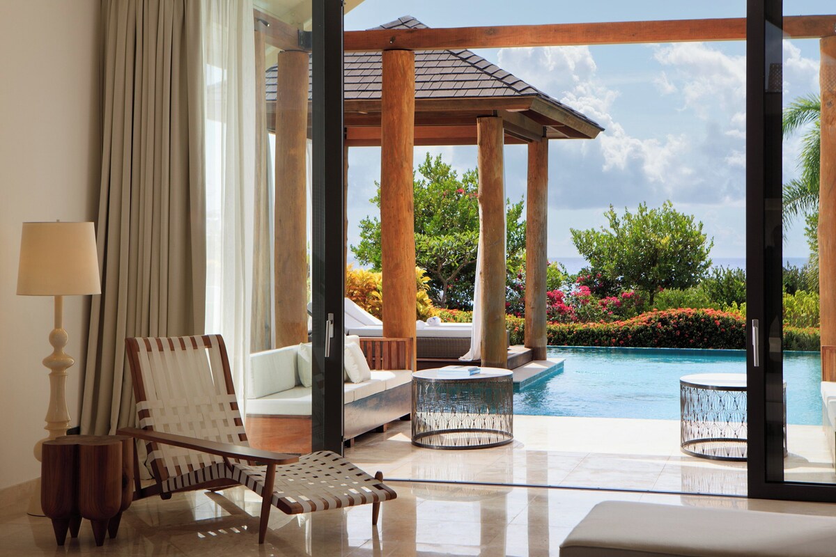 Una habitación moderna con vistas a una piscina, un sofá, una silla y una lámpara.