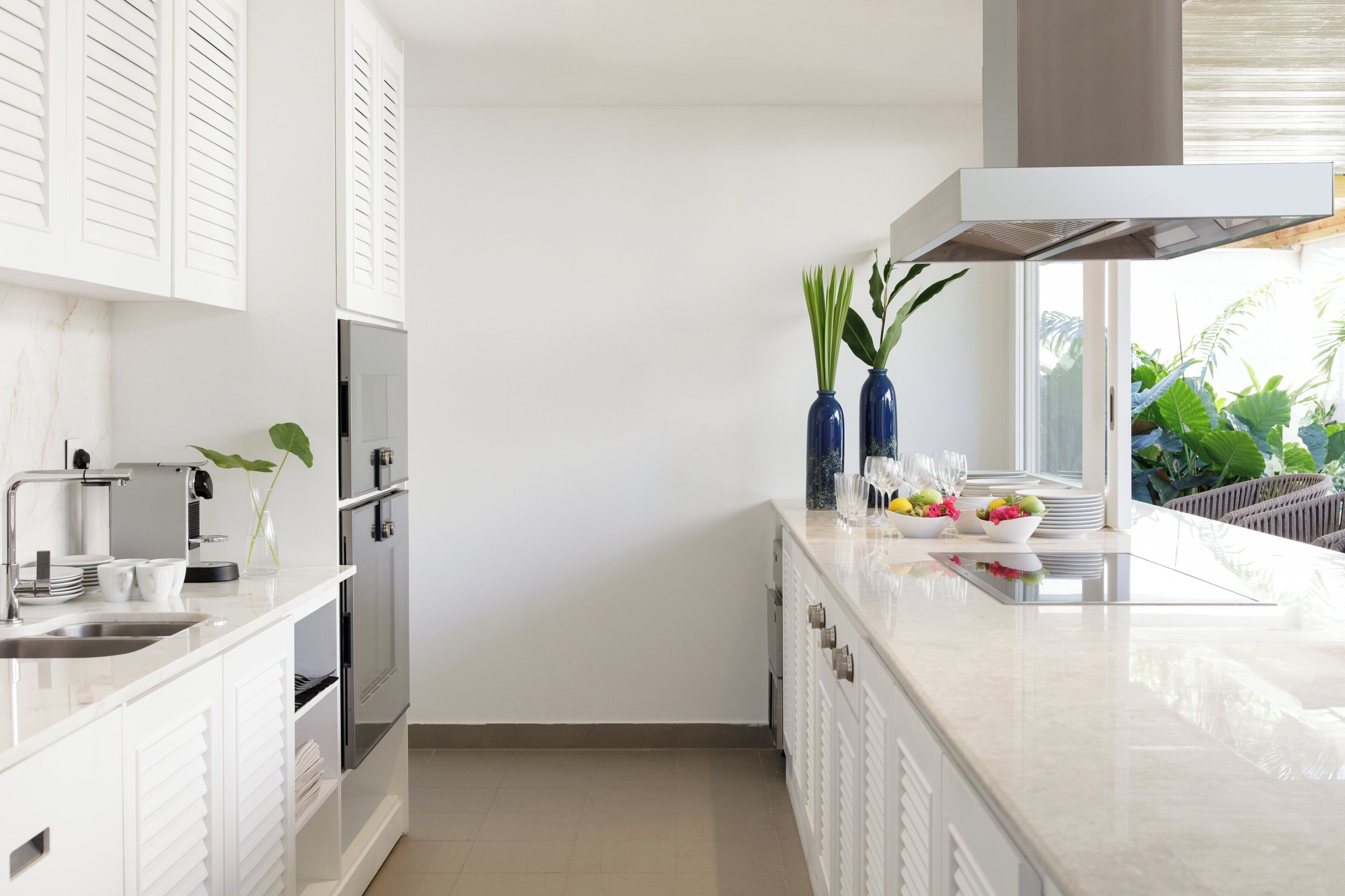 A modern kitchen with white cabinetry, a stainless steel sink, and a countertop with decorative items.