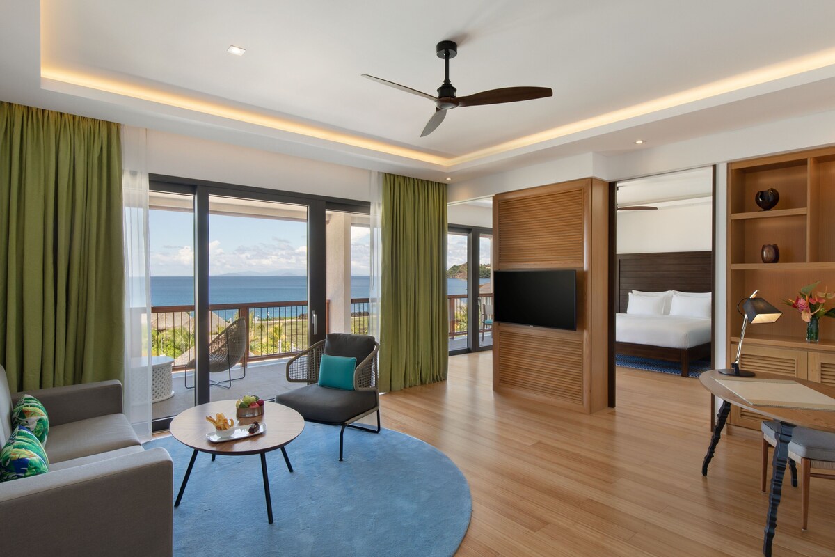Una habitación de hotel moderna con balcón, cama, escritorio y zona de estar.