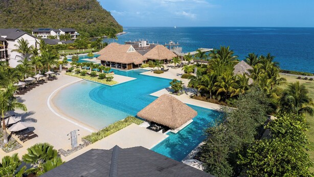 Ein Resort mit großem Schwimmbad, Strandbereich und Meerblick.
