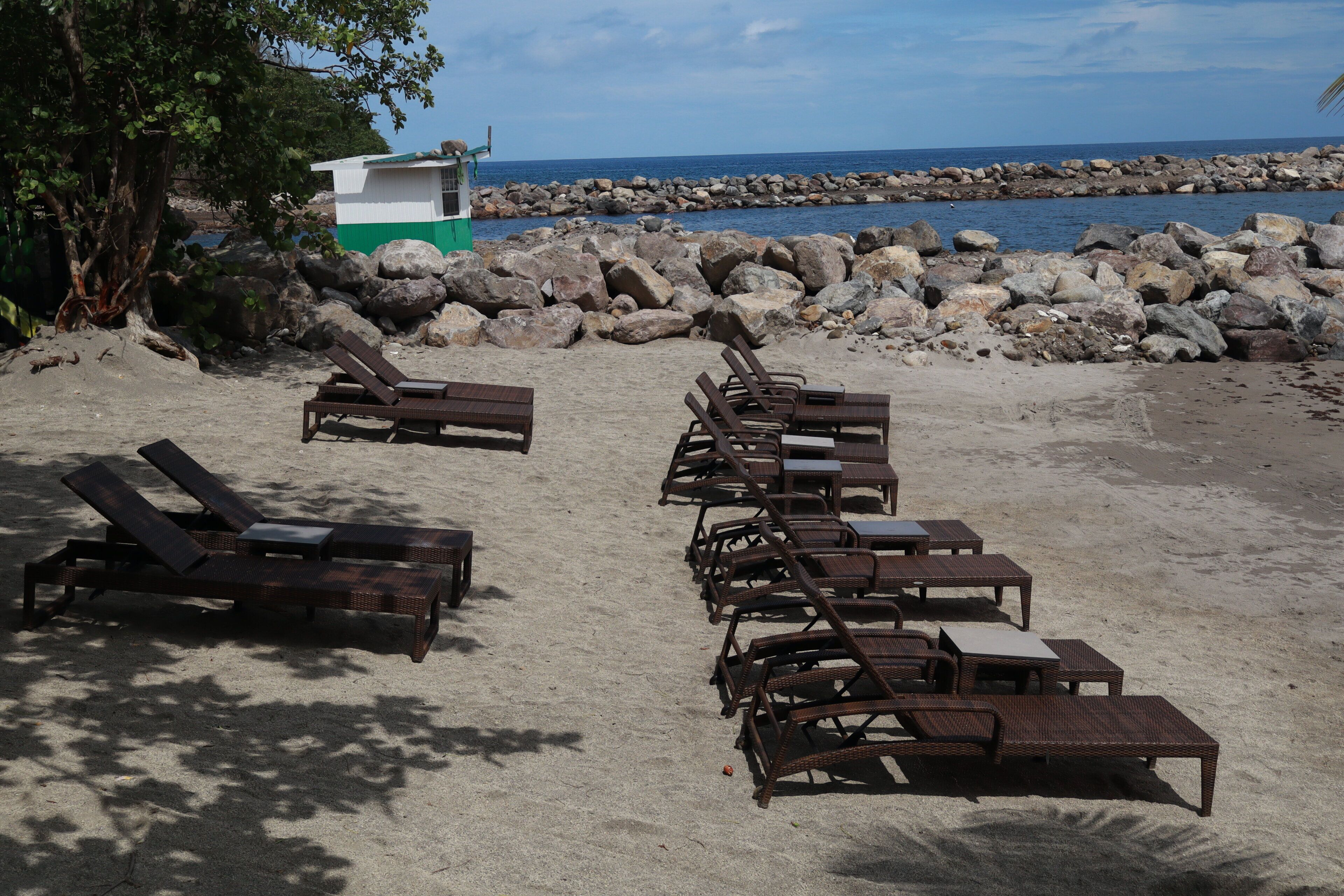 Una playa con filas de sillas de sol y una torre de salvavidas.