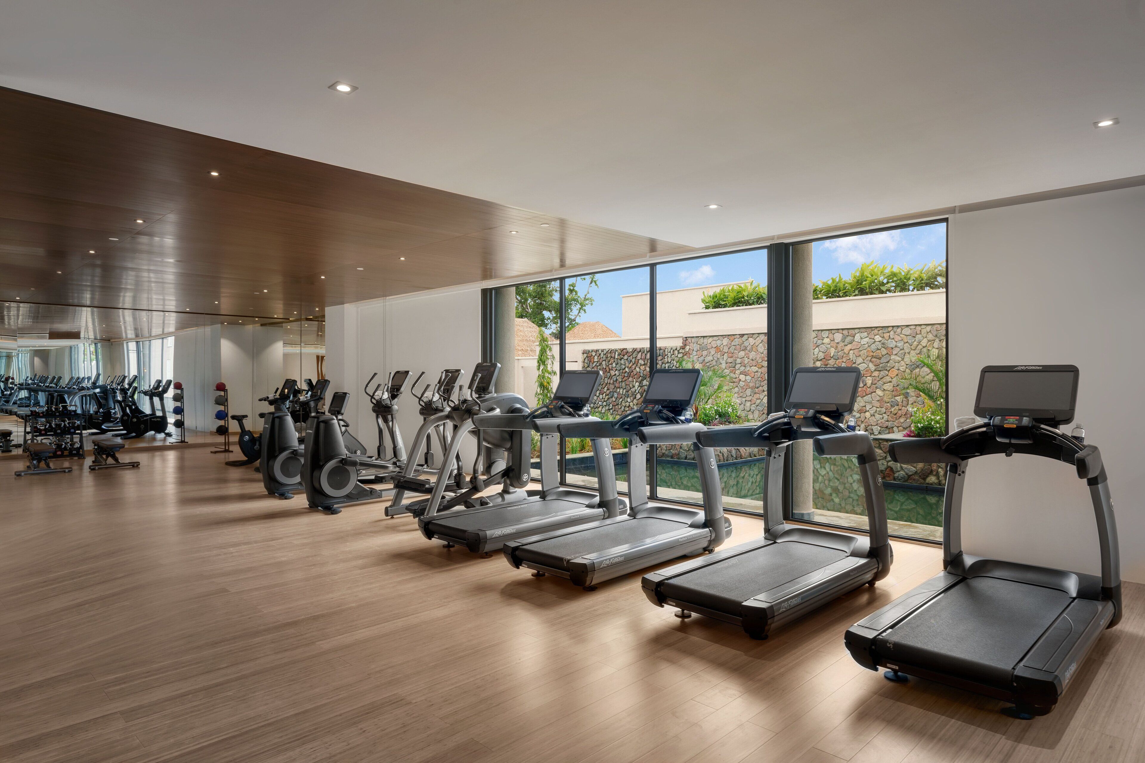 Une salle de sport équipée de tapis de course, de vélos d’appartement et d’autres appareils de musculation.