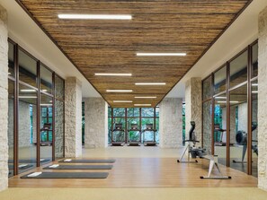 A modern gym with wooden beams, stone pillars, and exercise equipment.