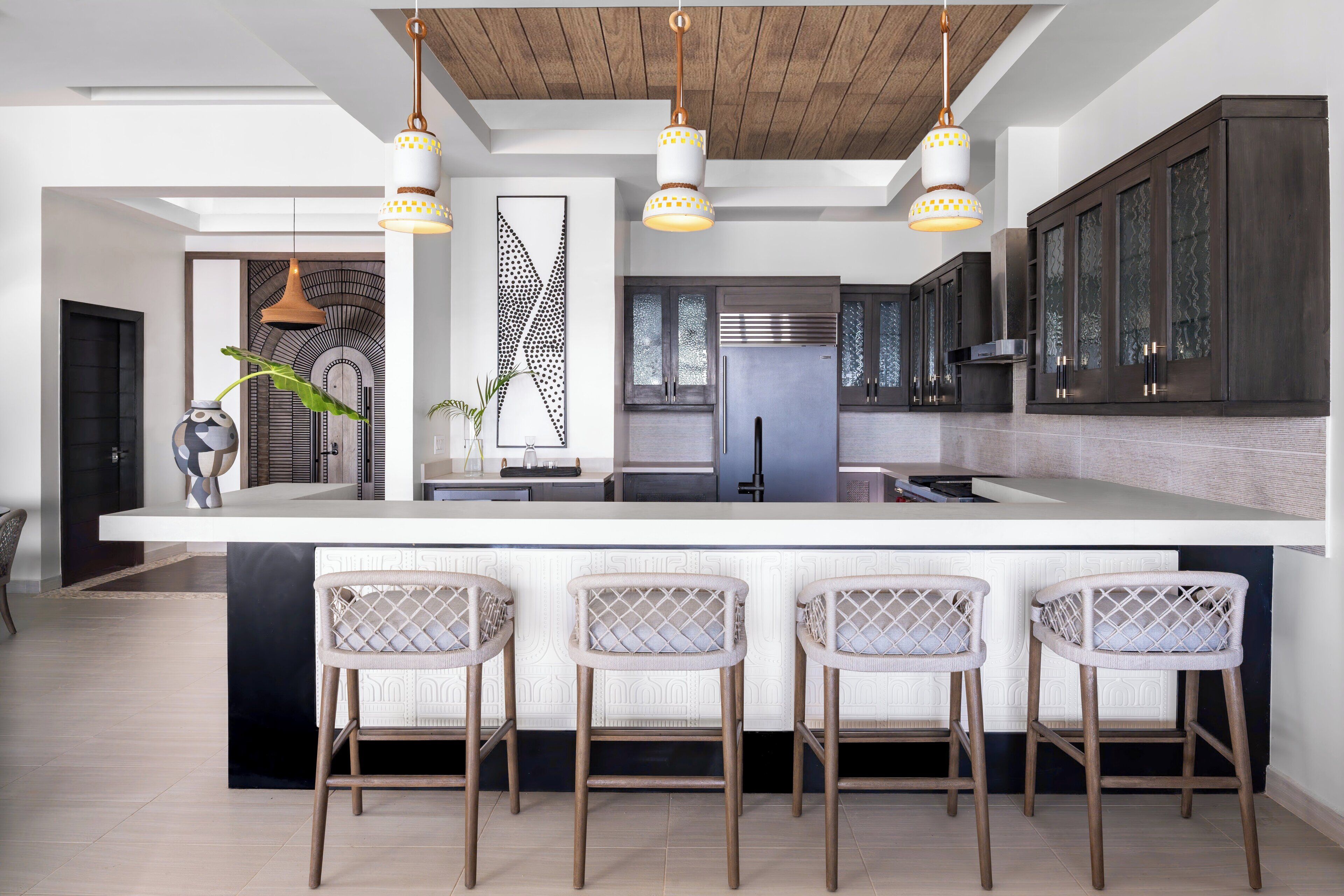 Une cuisine moderne dotée d’un grand îlot central, de tabourets de bar et de luminaires suspendus.