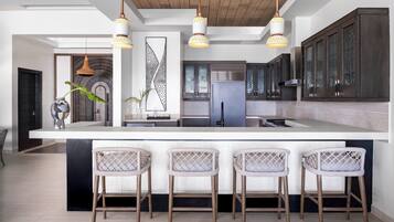 Una cocina moderna con una isla grande, taburetes de bar e iluminación colgante.