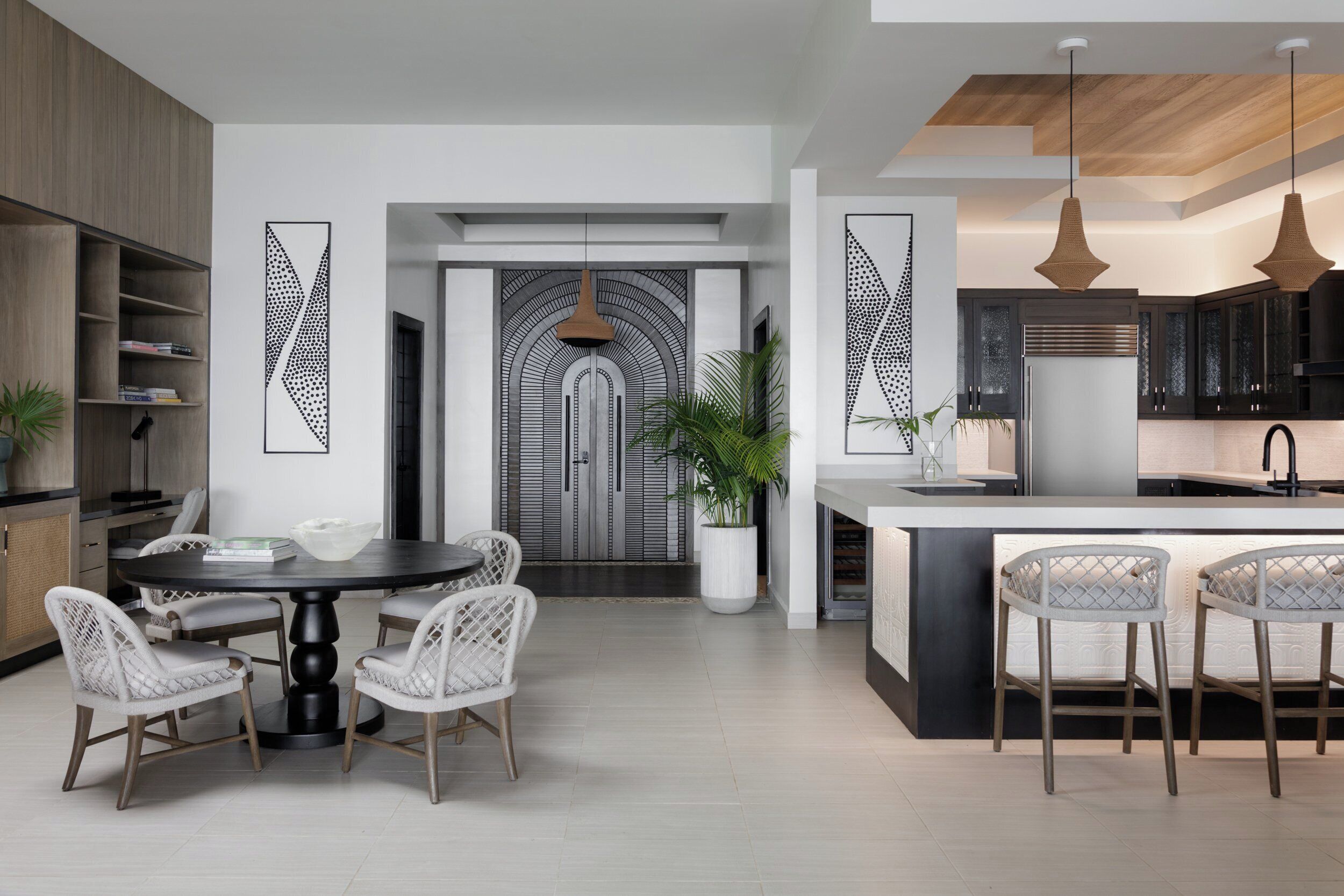 A modern kitchen with a central island, pendant lighting, and a dining area with a round table and chairs.