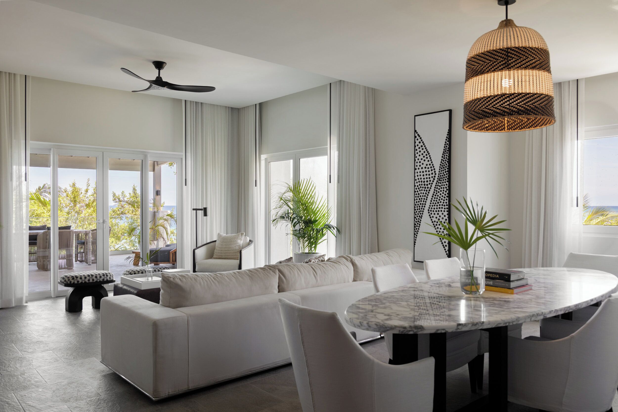 A modern living room with a large sofa, a round dining table, and a ceiling fan.