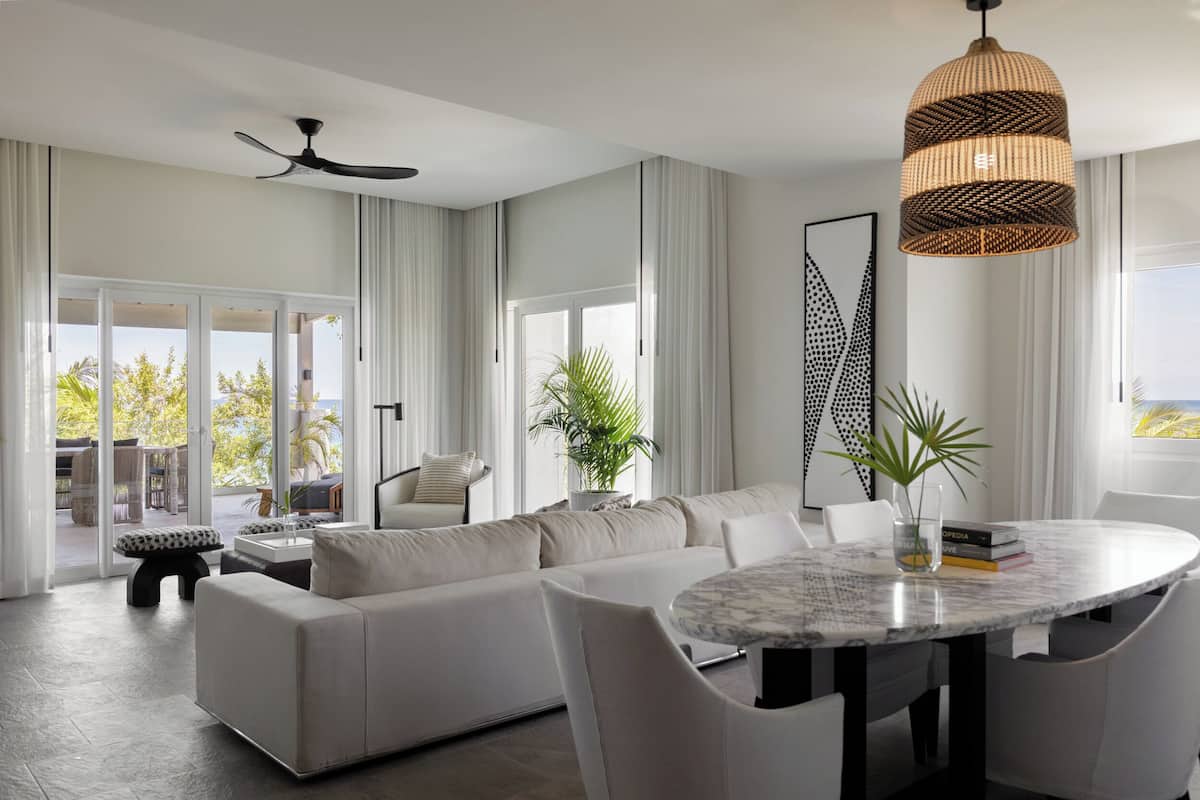 A modern living room with a large sofa, a round dining table, and a ceiling fan.