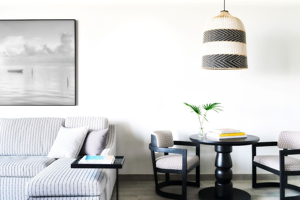 A modern living room with a striped sofa, a round table with chairs, a hanging pendant light, and a framed picture on the wall.