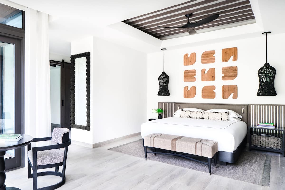 A modern bedroom with a large bed, a desk, and a chair.