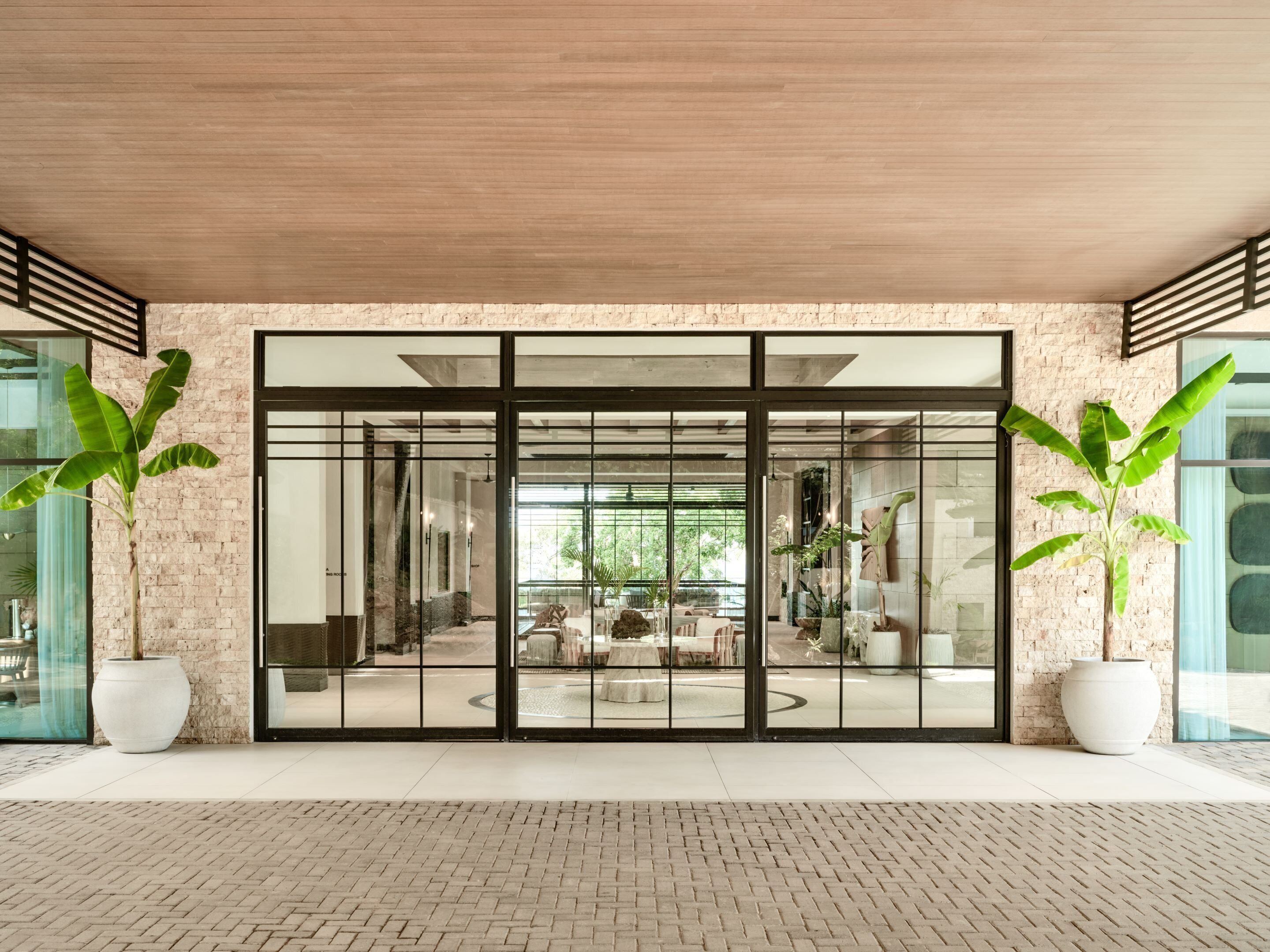 Un edificio moderno con ampie porte in vetro, pareti in mattoni e piante in vaso.