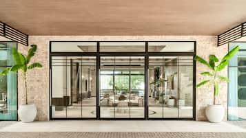 Un edificio moderno con ampie porte in vetro, pareti in mattoni e piante in vaso.