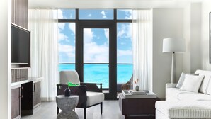 A modern hotel room with a large window offering a view of the ocean.