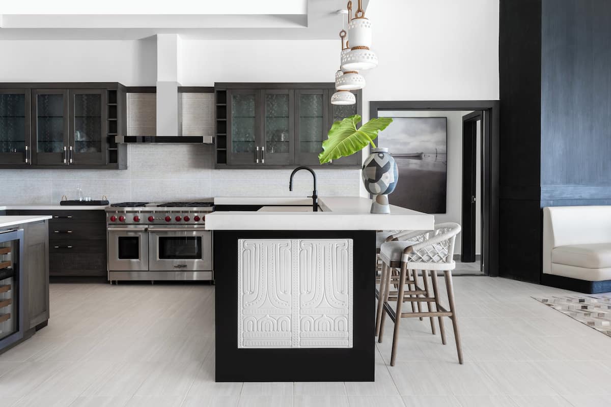 A modern kitchen with a central island, stainless steel appliances, and dark cabinetry.